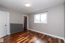 Neutral-toned room with wood-finish flooring, a white trim window, and white baseboards - 