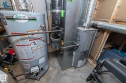 Mechanical room featuring a water heater, furnace, and exposed ductwork - 