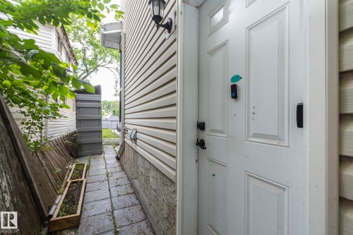 White paneled exterior door with black hardware, featuring a secure entry system - 11915 77 Street Nw, Edmonton, AB - Outdoor With Exterior