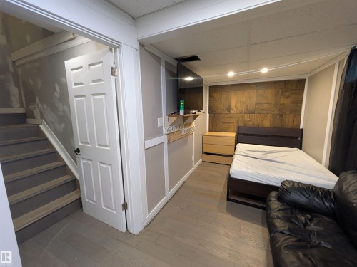 Interior room featuring wood-finish flooring and a decorative wood-panel accent wall - 11915 77 Street Nw, Edmonton, AB - Indoor Photo Showing Other Room