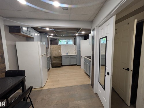 Kitchen area featuring light gray cabinetry, light wood-finish flooring, and white appliances - 11915 77 Street Nw, Edmonton, AB - Indoor Photo Showing Basement