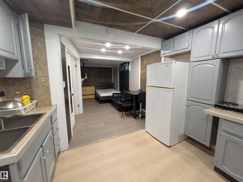 Compact kitchen featuring light gray cabinetry, laminate countertops, and a stainless steel sink - 11915 77 Street Nw, Edmonton, AB - Indoor Photo Showing Other Room