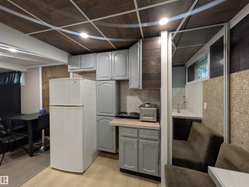 Compact kitchen area featuring light gray cabinetry and a white refrigerator - 11915 77 Street Nw, Edmonton, AB - Indoor Photo Showing Basement