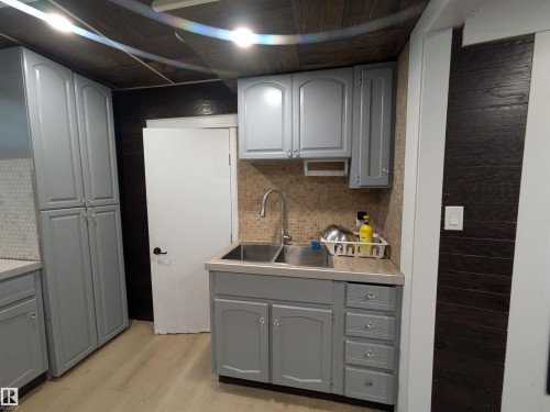 Compact kitchen area featuring light gray cabinetry, a double basin stainless steel sink, and a mosaic tile backsplash - 11915 77 Street Nw, Edmonton, AB - Indoor