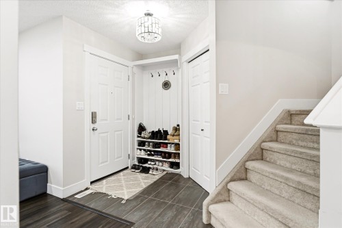 Entryway featuring tiled flooring, a built-in coat rack with hooks, and a paneled front door - 4317 152 Avenue Nw, Edmonton, AB - Indoor Photo Showing Other Room