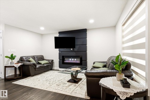 Living area featuring dark wood-finish flooring, recessed lighting, and a modern wall-mounted electric fireplace - 4317 152 Avenue Nw, Edmonton, AB - Indoor With Fireplace