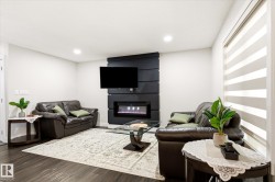 Living area featuring dark wood-finish flooring, recessed lighting, and a modern wall-mounted electric fireplace - 