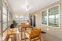 Enclosed sunroom featuring multiple large windows, wall-to-wall carpeting, a ceiling-mounted light fixture, and a sliding glass door - 