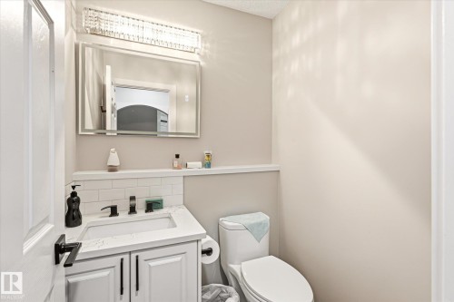 Bathroom featuring a white vanity with a quartz-finish countertop, matte black faucet, and subway tile backsplash - 4317 152 Avenue Nw, Edmonton, AB - Indoor Photo Showing Bathroom