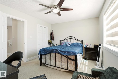 Interior room featuring neutral wall paint and carpeting, a ceiling fan with integrated lighting, a window with horizontal blinds, and a bi-fold closet door - 4317 152 Avenue Nw, Edmonton, AB - Indoor Photo Showing Bedroom