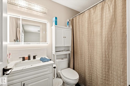 Bathroom featuring a white vanity with a countertop, an integrated sink, and a matte black faucet - 4317 152 Avenue Nw, Edmonton, AB - Indoor Photo Showing Bathroom