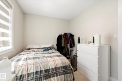 Neutral-toned bedroom featuring a window with horizontal blinds and light-colored carpeting - 