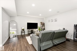 Spacious room featuring wood-finish flooring, recessed ceiling lighting, a pitched ceiling, and white baseboards - 