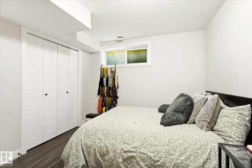 Light-filled room featuring a large bi-fold closet, a high window, wood-finish flooring, and a neutral wall palette - 4317 152 Avenue Nw, Edmonton, AB - Indoor Photo Showing Bedroom