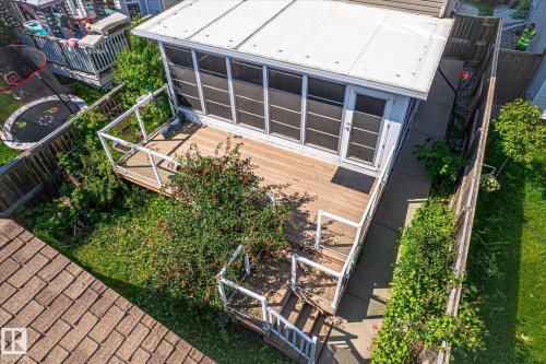 Expansive wood-finish deck with white railings, featuring a screened-in porch with multiple windows and a glass-paneled door - 4317 152 Avenue Nw, Edmonton, AB - Outdoor With Exterior