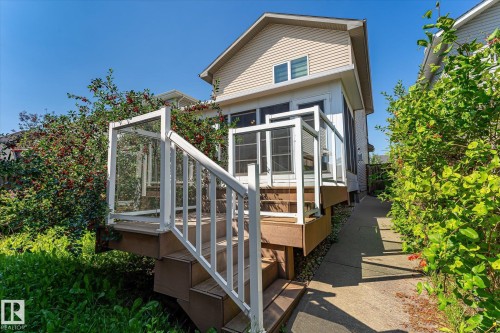 Rear exterior featuring a screened-in porch with an exterior staircase, wood-finish decking, and white railing with glass panels - 4317 152 Avenue Nw, Edmonton, AB - Outdoor