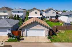 Detached two-car garage with light-colored siding and a brown shingled roof - 