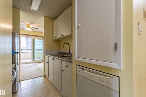 Compact kitchen featuring light-toned cabinetry, a stainless steel sink with a high-arc faucet, and tiled flooring - #1210 10140 120 St Nw, Edmonton, AB - Indoor Photo Showing Kitchen