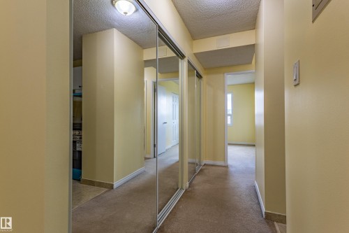 Hallway featuring mirrored closet doors and neutral carpeting - #1210 10140 120 St Nw, Edmonton, AB - Indoor Photo Showing Other Room