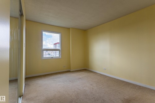 Carpeted room with a single window, white trim, and mirrored sliding closet doors - #1210 10140 120 St Nw, Edmonton, AB - Indoor Photo Showing Other Room