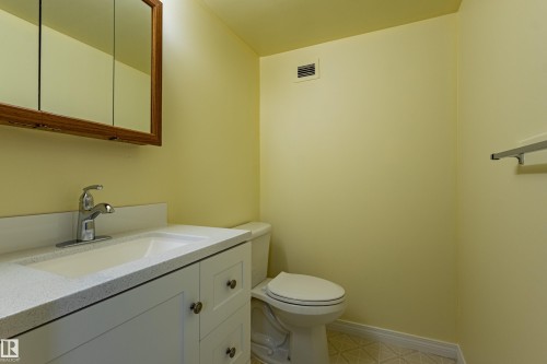 Bathroom featuring a white vanity with integrated sink, chrome faucet, and wood-framed medicine cabinet - #1210 10140 120 St Nw, Edmonton, AB - Indoor Photo Showing Bathroom