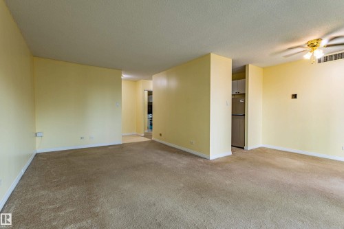 Carpeted living area with light yellow walls and white baseboards - #1210 10140 120 St Nw, Edmonton, AB - Indoor Photo Showing Other Room