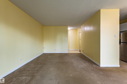 Spacious room featuring light yellow walls and brown carpet - #1210 10140 120 St Nw, Edmonton, AB - Indoor Photo Showing Other Room