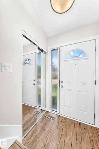 Entryway with wood-finish flooring, a white paneled door featuring an arched transom window, and an adjacent sidelight - 3119 144 Avenue Nw, Edmonton, AB - Indoor Photo Showing Other Room