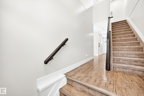Carpeted staircase with a dark wood handrail and a contemporary dark wood newel post - 3119 144 Avenue Nw, Edmonton, AB - Indoor Photo Showing Other Room
