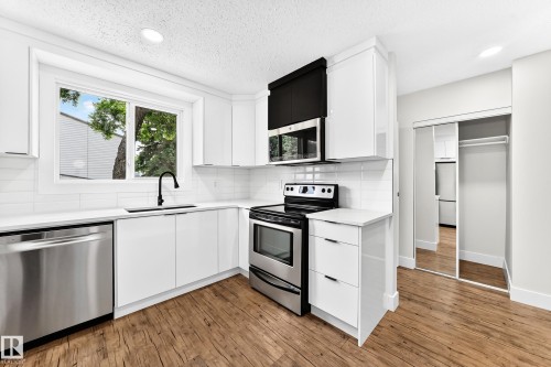 Modern kitchen featuring white cabinetry, stainless steel appliances, wood-finish flooring, and a subway tile backsplash - 3119 144 Avenue Nw, Edmonton, AB - Indoor Photo Showing Kitchen With Upgraded Kitchen