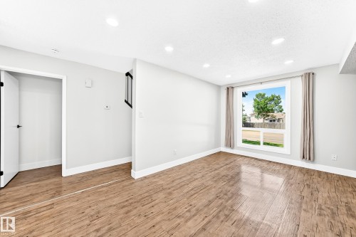 Spacious room with wood-finish flooring, recessed lighting, and a large window with white trim - 3119 144 Avenue Nw, Edmonton, AB - Indoor Photo Showing Other Room