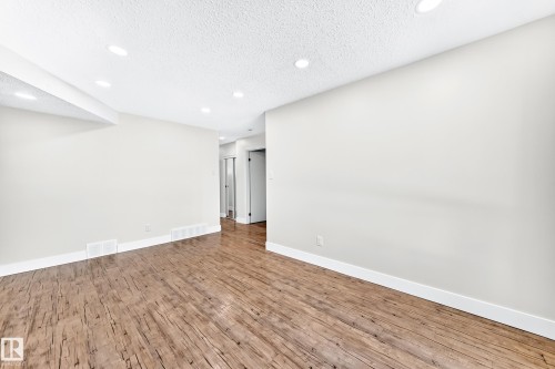 Spacious room featuring wood-finish flooring, recessed lighting, and crisp white baseboards - 3119 144 Avenue Nw, Edmonton, AB - Indoor Photo Showing Other Room