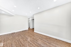 Spacious room featuring wood-finish flooring, recessed lighting, and crisp white baseboards - 