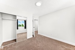 Carpeted room featuring a mirrored sliding closet door, white walls, and a round flush-mount ceiling light - 