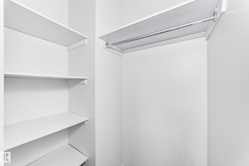 Built-in closet system featuring multiple white shelving units and a chrome hanging rod - 3119 144 Avenue Nw, Edmonton, AB - Indoor With Storage
