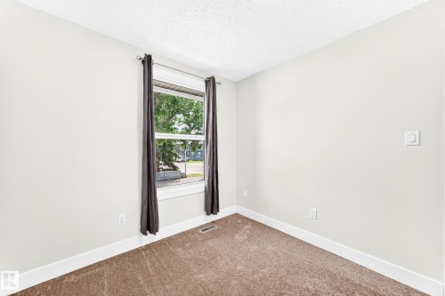 Carpeted room with a double-pane window, white trim, light-colored walls, and a textured ceiling - 3119 144 Avenue Nw, Edmonton, AB - Indoor Photo Showing Other Room