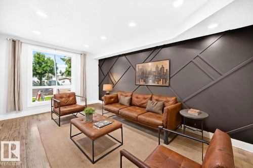 Living area featuring an accent wall with geometric paneling, wood-finish flooring, recessed lighting, and a large window - 3119 144 Avenue Nw, Edmonton, AB - Indoor Photo Showing Living Room
