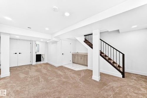 Finished lower level featuring carpeted flooring, recessed lighting, and a contemporary staircase with dark wood-finish treads and black metal balusters - 3119 144 Avenue Nw, Edmonton, AB - Indoor Photo Showing Other Room