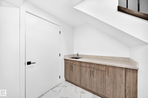 Integrated wet bar with wood-finish cabinetry and light-toned countertop - 3119 144 Avenue Nw, Edmonton, AB - Indoor Photo Showing Other Room
