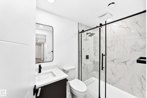 Bathroom featuring a glass-enclosed shower with black trim, a large format marbled tile surround, a built-in shower niche, and a rain shower head - 3119 144 Avenue Nw, Edmonton, AB - Indoor Photo Showing Bathroom