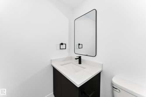 Modern vanity with a white countertop and integrated sink, matte black faucet, and coordinating black-framed mirror - 3119 144 Avenue Nw, Edmonton, AB - Indoor Photo Showing Bathroom