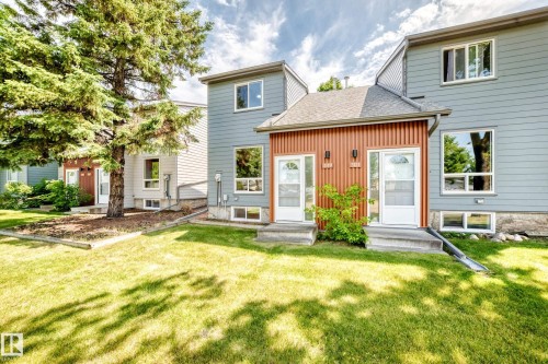 Exterior featuring light blue siding, a brown vertical plank accent wall, and multiple windows - 3119 144 Avenue Nw, Edmonton, AB - Outdoor
