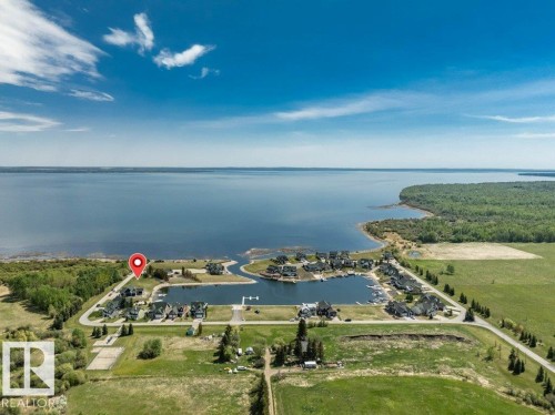 Waterfront community featuring an integrated marina, structured boat slips, paved roadways, and green spaces, bordered by natural wooded areas and expansive water - 12 Sunset Harbour, Rural Wetaskiwin County, AB 