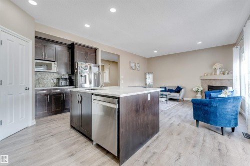 Open-concept living space featuring wood-finish flooring, a kitchen island with a white countertop, dark wood cabinetry, and recessed lighting - 121 64 Street Sw, Edmonton, AB - Indoor Photo Showing Kitchen