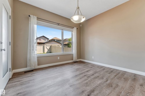 Spacious room featuring wood-finish flooring, a large multi-pane window, and a frosted glass-paneled door - 121 64 Street Sw, Edmonton, AB - Indoor Photo Showing Other Room