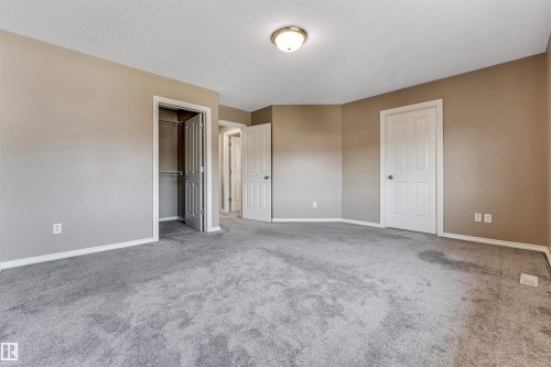 Spacious room featuring gray carpeting, neutral wall tones, white baseboards, and a semi-flush mount ceiling light fixture - 121 64 Street Sw, Edmonton, AB - Indoor Photo Showing Other Room