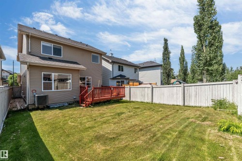 Expansive backyard featuring a manicured lawn, a red-stained wood deck, and a tall wood fence - 121 64 Street Sw, Edmonton, AB - Outdoor