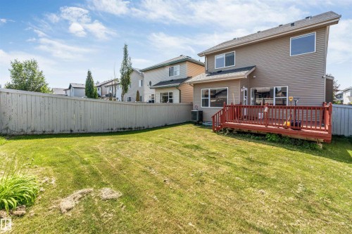 Expansive backyard featuring a private wood fence, a large deck with a red finish, and mature landscaping - 121 64 Street Sw, Edmonton, AB - Outdoor With Deck Patio Veranda