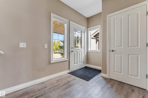 Entryway featuring a decorative glass front door, side windows, wood-finish flooring, and painted walls - 121 64 Street Sw, Edmonton, AB - Indoor Photo Showing Other Room
