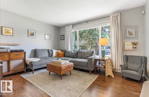 Spacious living area featuring wood-finish flooring, a large picture window, and a light-toned ceiling - 4718 35 Avenue Nw, Edmonton, AB - Indoor Photo Showing Living Room